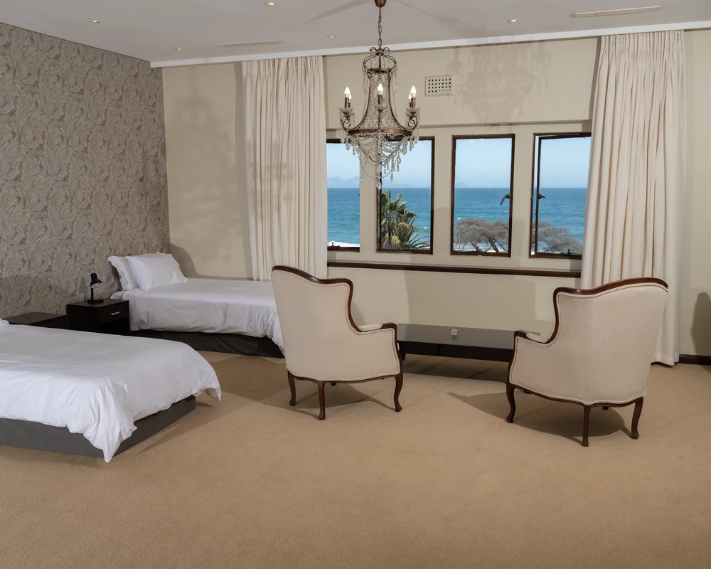 Spacious double room with two beds, armchairs and a sea view.