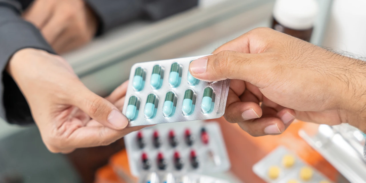 One person hands over prescription medicine capsules to another, representing dependency and patterns associated with medicine addiction.