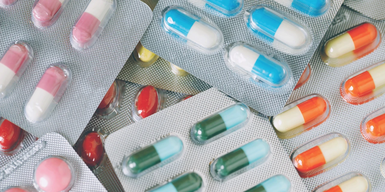 Different prescription drugs in colourful blister packs and capsules spread across a surface, illustrating medication use and the risks of misuse.
