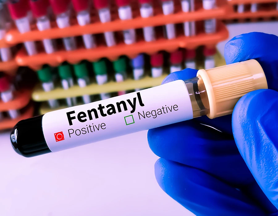 Blood sample marked positive for fentanyl in a gloved hand, illustrating fentanyl overdose