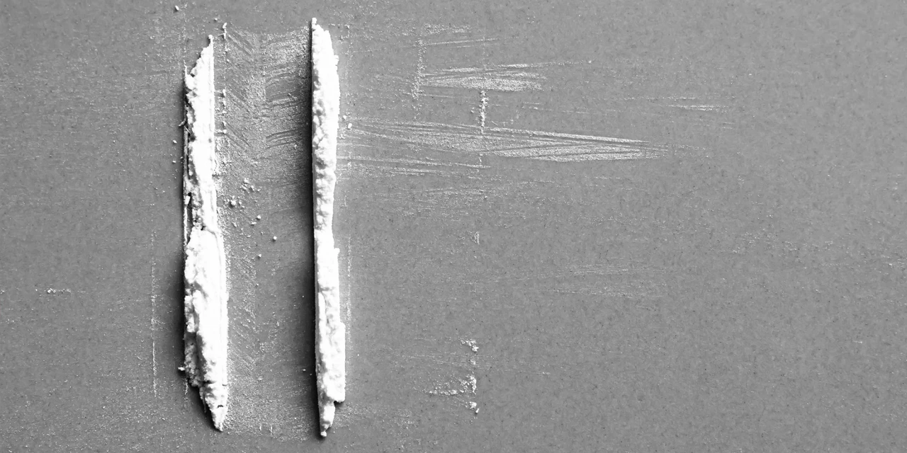 Two lines of white stimulant powder prepared on a flat surface, representing recreational drug use and the risks associated with speed addiction.