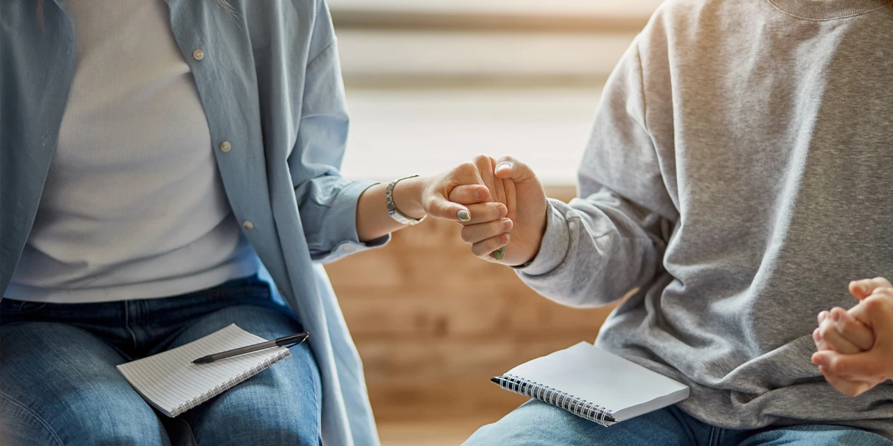 Two people hold hands during a therapy session, representing trust, emotional support and recovery during dual diagnosis treatment and mental health care.