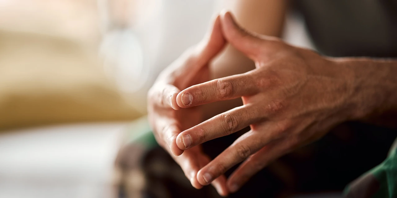 Close-up of tense hands during a conversation, symbolising stress, emotional overwhelm and the physical impact PTSD can have on your body and mind.
