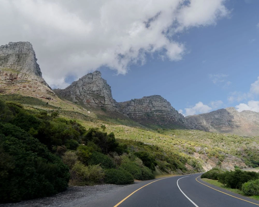 Kronkelende asfaltweg door groene heuvels bij Kaapstad, Zuid-Afrika.