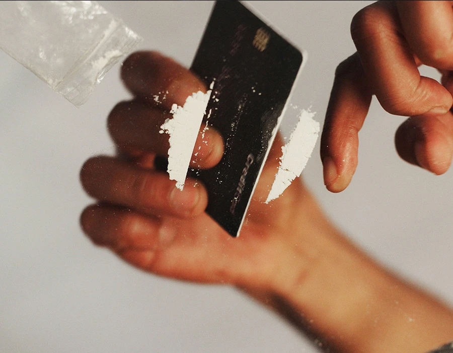 Hand holding a card with cocaine, illustrating cocaine addiction and rehabilitation.
