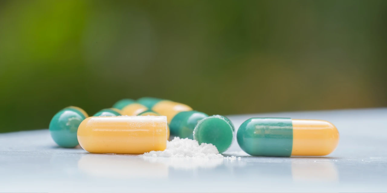 Opened tramadol capsules with white powder spilled onto a surface, illustrating misuse of medication and the dangers of tramadol addiction.