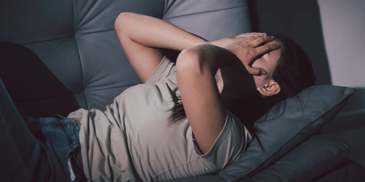 A woman sits on a sofa, illustrating emotional distress and behaviour linked to pregabalin addiction.