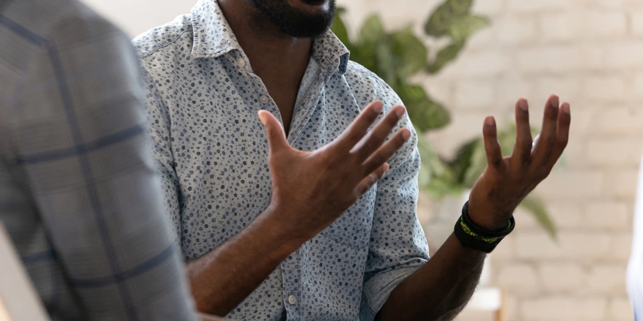 A man speaks openly during a support meeting, sharing information about his recovery journey and mental health challenges in a safe environment.