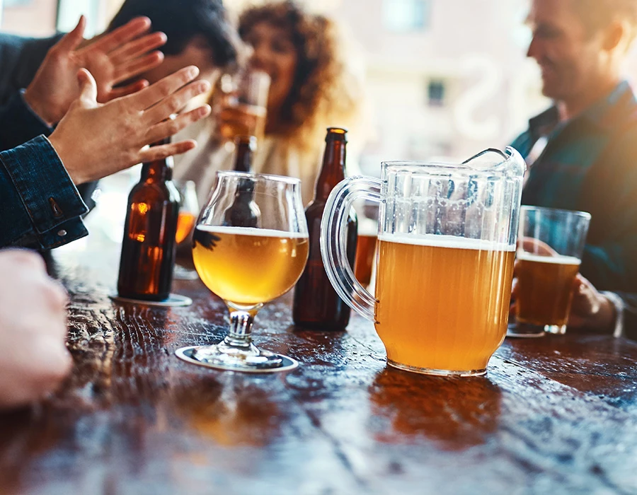 Groep mensen drinkt bier samen aan tafel in sociale setting.