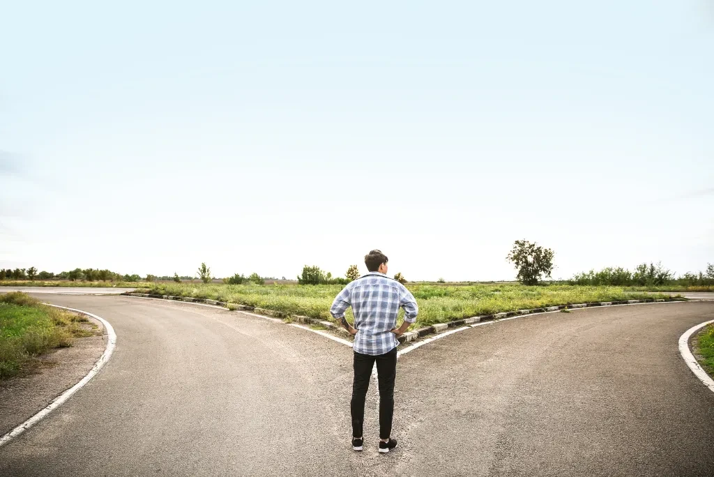 person-at-cross-roads A person in a checkered shirt standing at a cross roads, contemplating which way to go.
